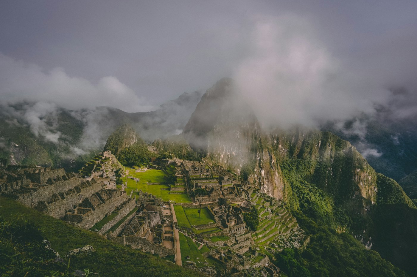 Machu Picchu terraces and stone ruins beneath steep green Andean peaks