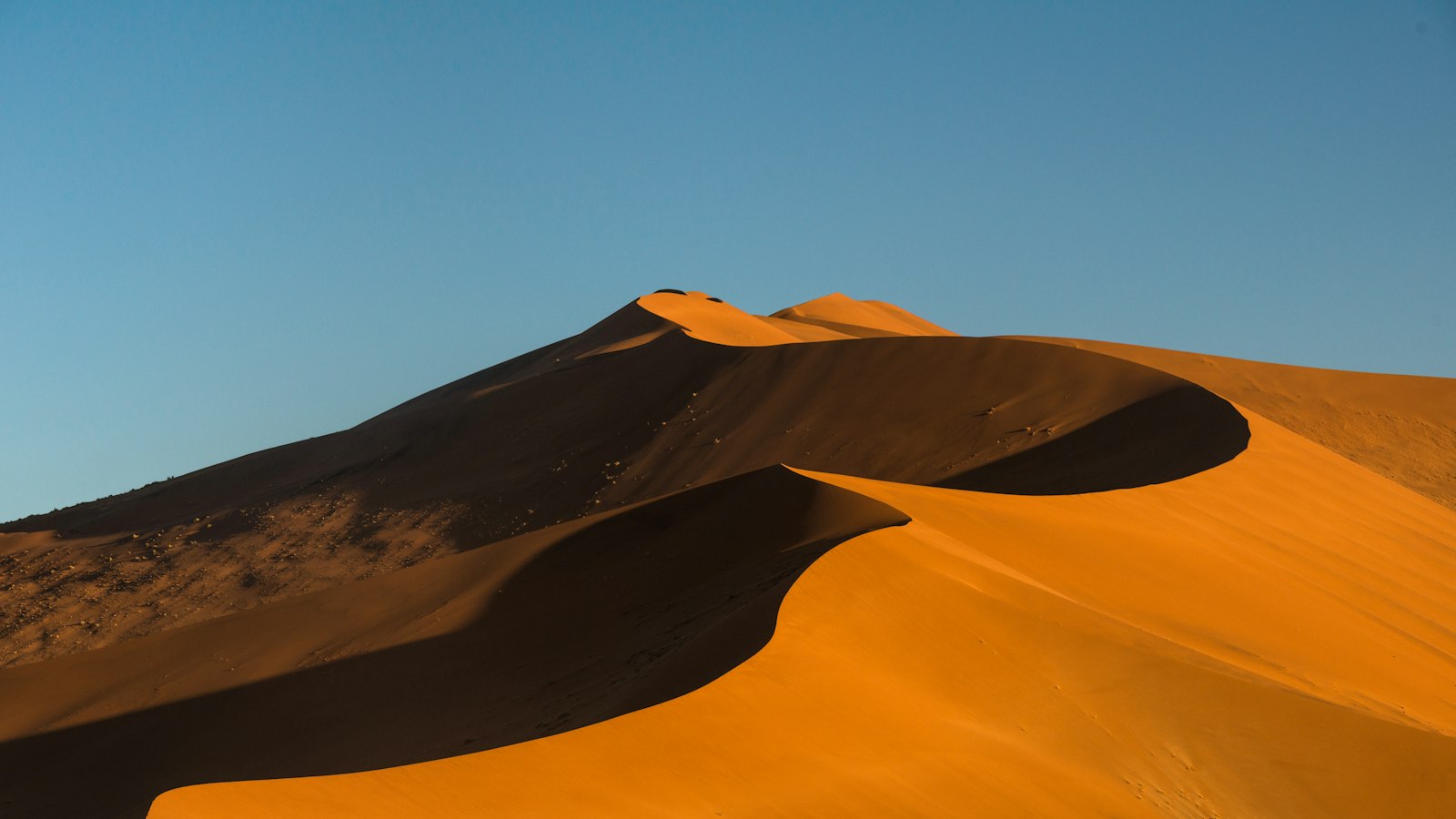 Towering orange dunes under a clear sky in Sossusvlei, Namibia